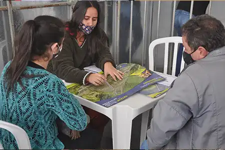 Corretor mostrando material de venda de loteamento para seu cliente